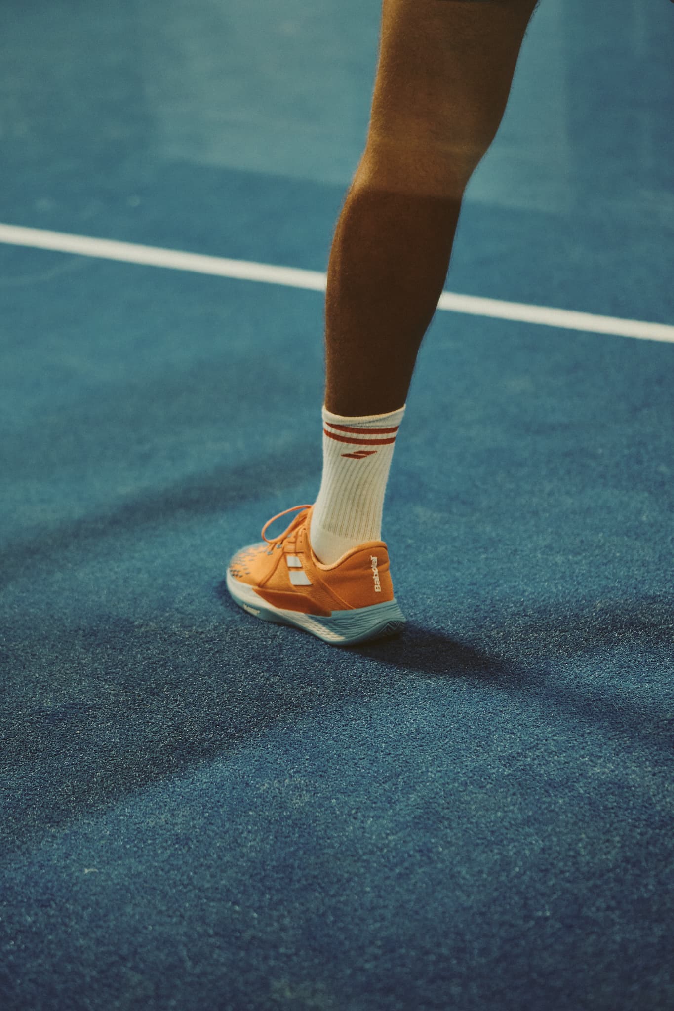 Joueur sur une piste du Spark, chaussure orange sur le gazon bleu